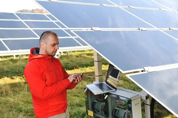 Un homme sous des panneaux solaires près d'un ordinateur