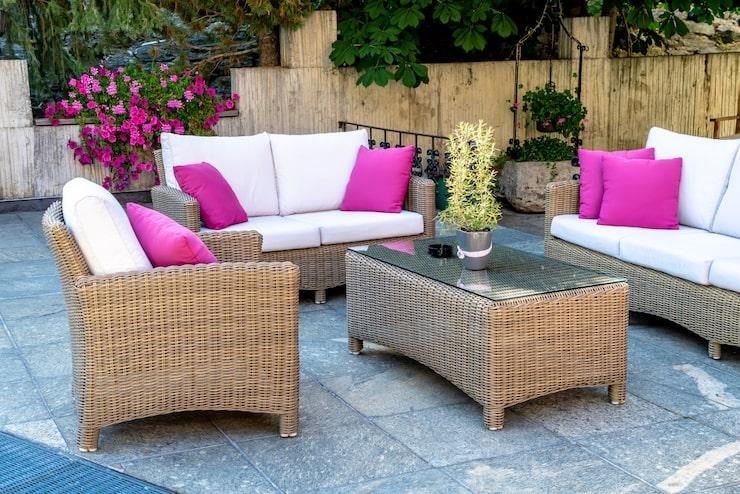 Un mobilier de jardin en rotin avec des coussins blancs et roses