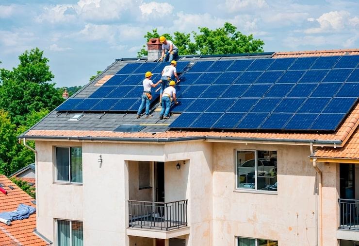 4 artisans qui installent des panneaux solaires sur un toit de maison