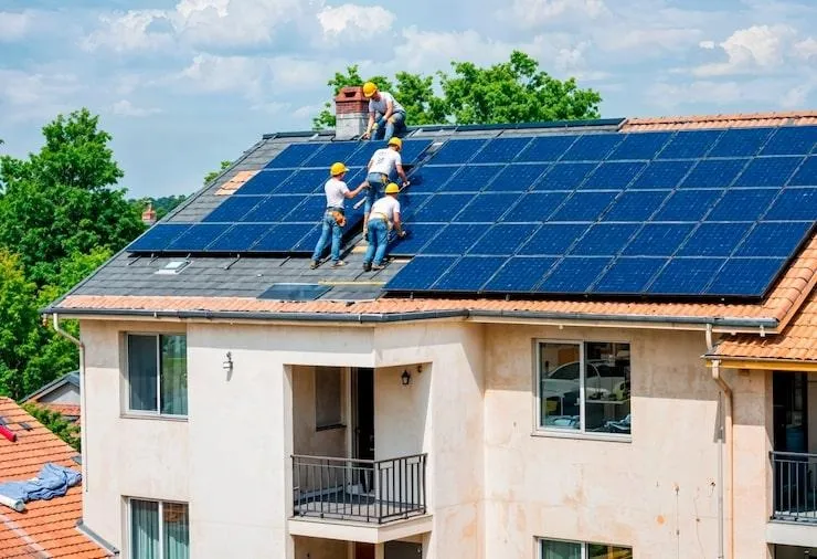 4 artisans qui installent des panneaux solaires sur un toit de maison