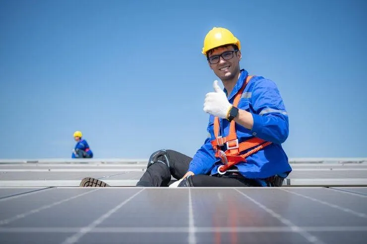 Un homme avec un casque et des équipements de sécurité qui installe des panneaux solaires