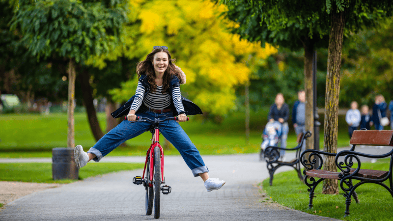 Une femme qui fait du vélo dans un parc et qui est contente