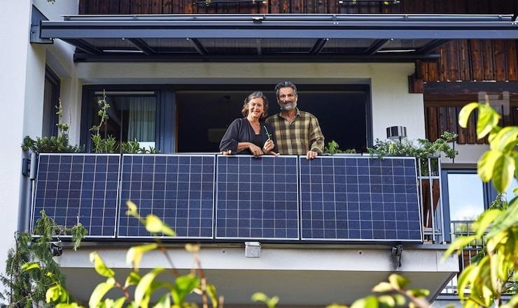 Un couple sur un balcon où sont installés des panneaux solaires
