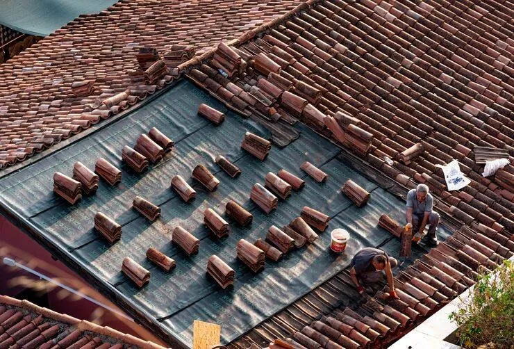 Deux hommes qui installent de tuiles sur une toiture