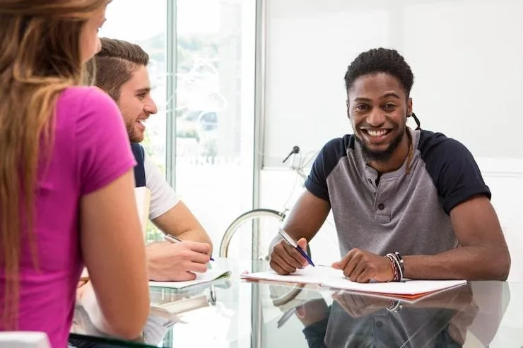 Un homme qui signe un contrat d'assurance pour vélo cargo face à deux personnes