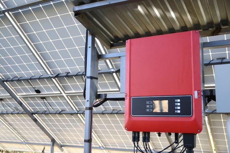Un onduleur photovoltaïque rouge sous un panneau