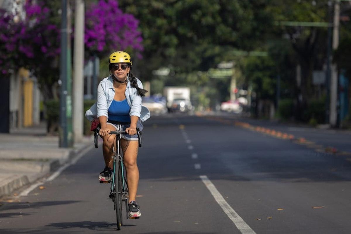 Une femme qui roule avec un vélo électrique de location en ville. 