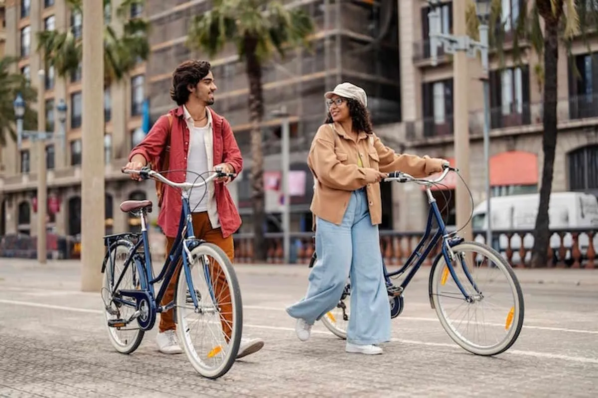 Un homm et une femme qui marche dans la rue en pavée en tenant chacun un vélo électrique