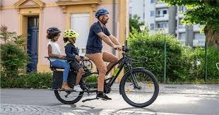 Un homme qui roule sur un vélo Nebula de Brumaire dans la ville avec deux enfants