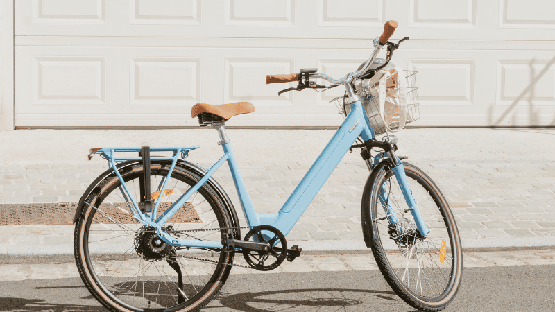 Vélo électrique Folio de Brumaire de couleur bleu persan devant un garage.