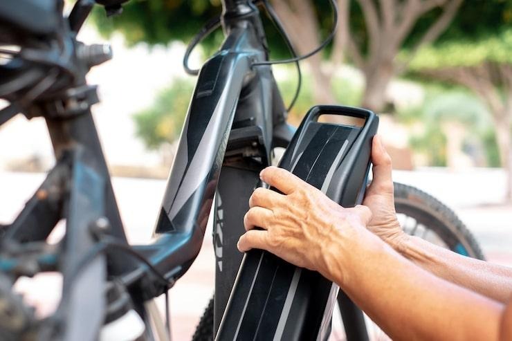 Un homme qui prend la batterie d'un véolo électrique de ville