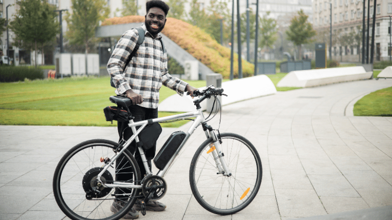 Un homme tient son vélo électrique en ville.