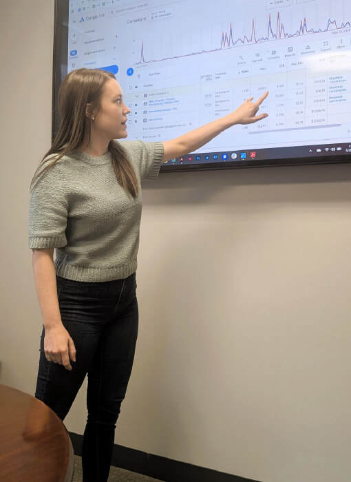 woman pointing at screen of statistics about contract manufacturer