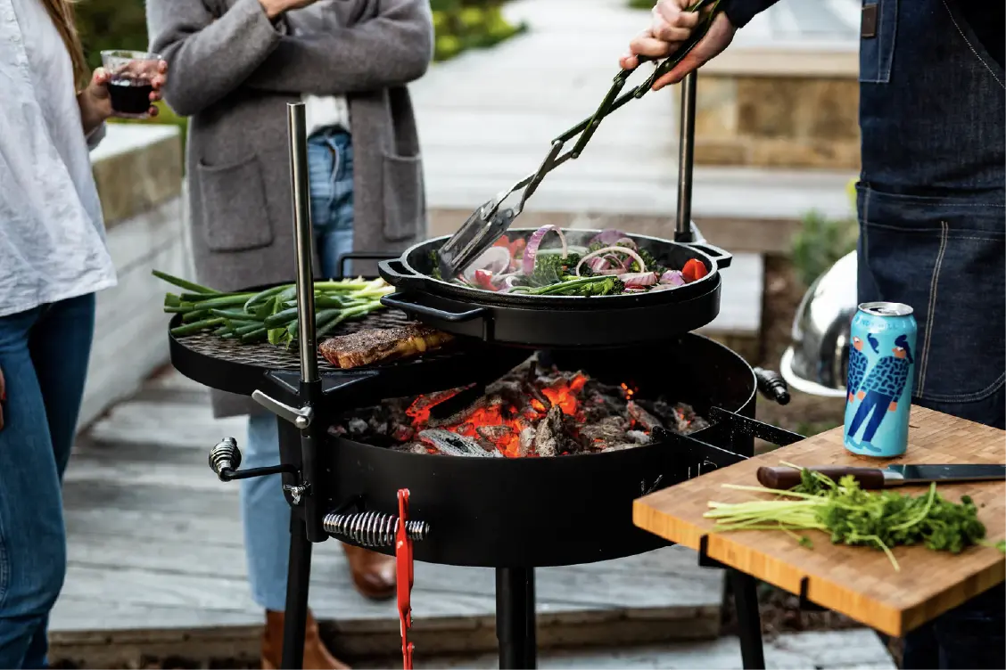 KUDU open fire grill being used for grilling with a group of friends