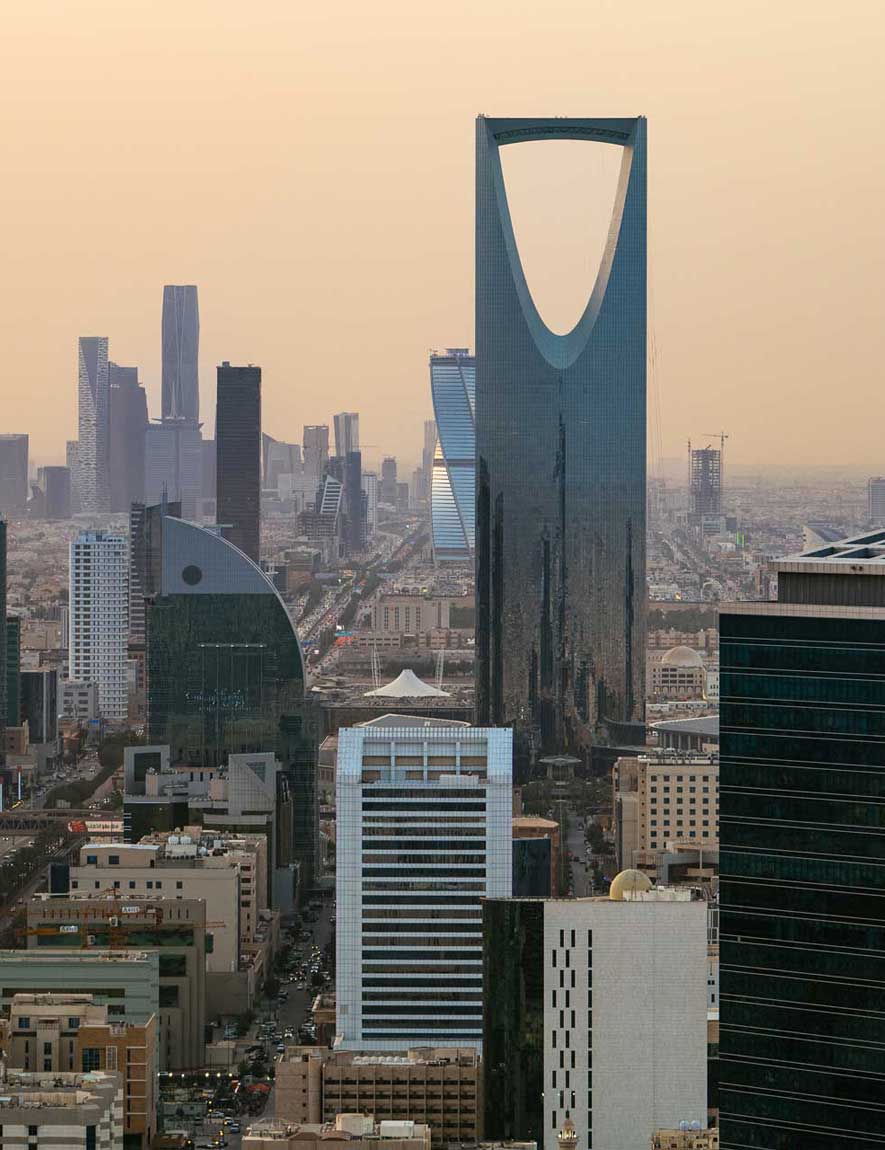 Woman with curly hair standing and looking at the pyramids of Giza at sunset.