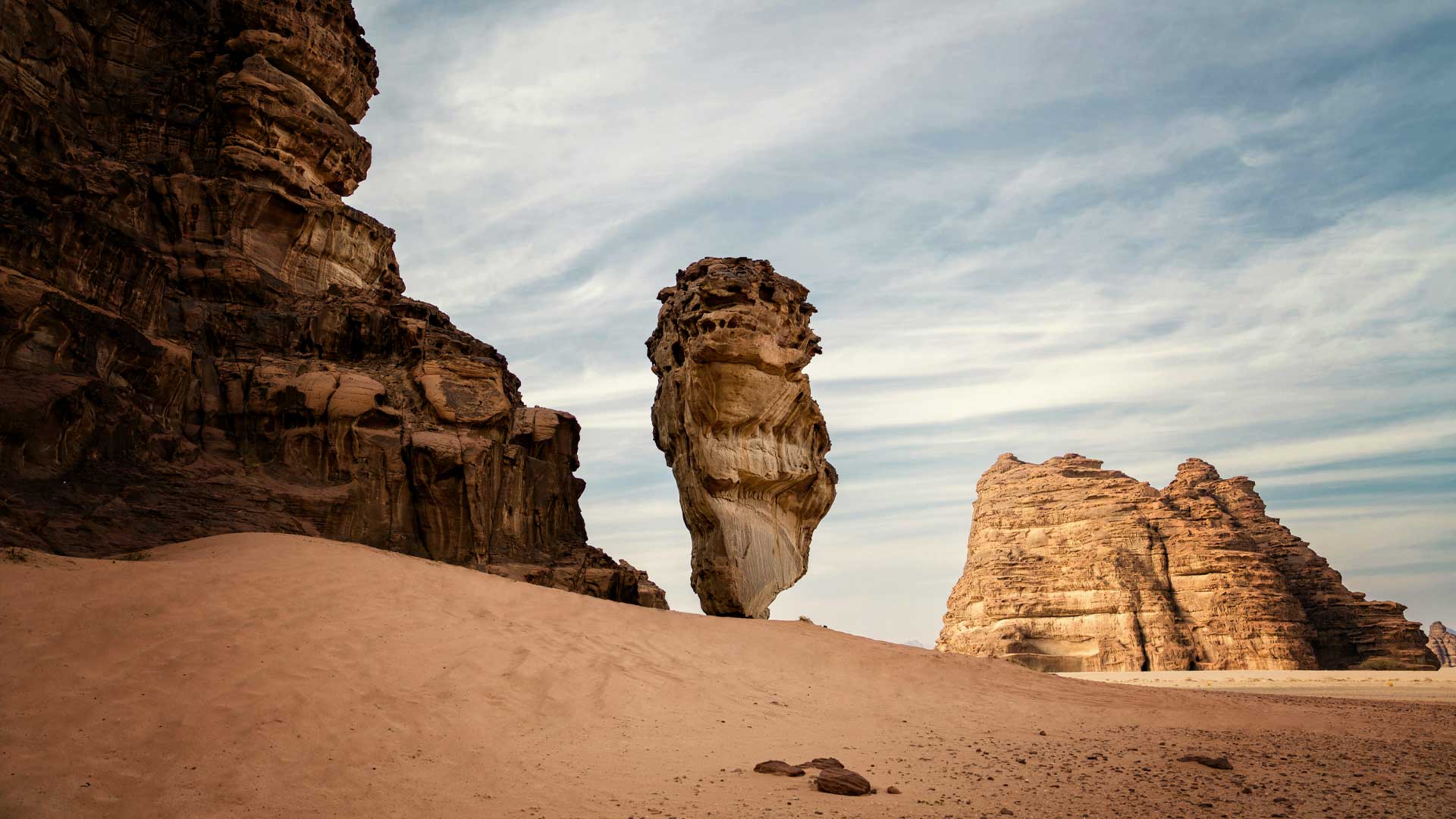 Desert landscape with unique tall rock formations under a cloudy sky.
