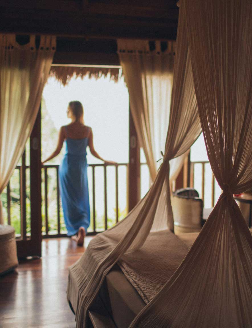 Woman with curly hair standing and looking at the pyramids of Giza at sunset.