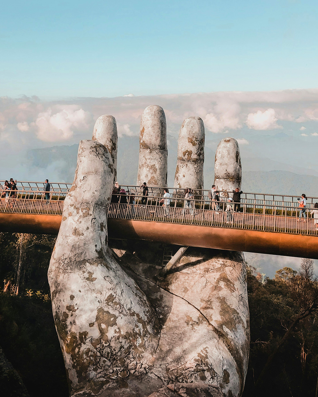 Golden Bridge in Vietnam held up by two giant stone hands with people walking along the bridge.