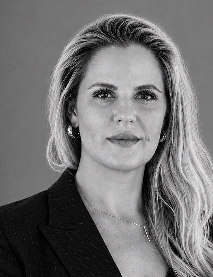 Black and white portrait of a woman with long hair, hoop earrings, and a cross necklace wearing a pinstripe blazer.