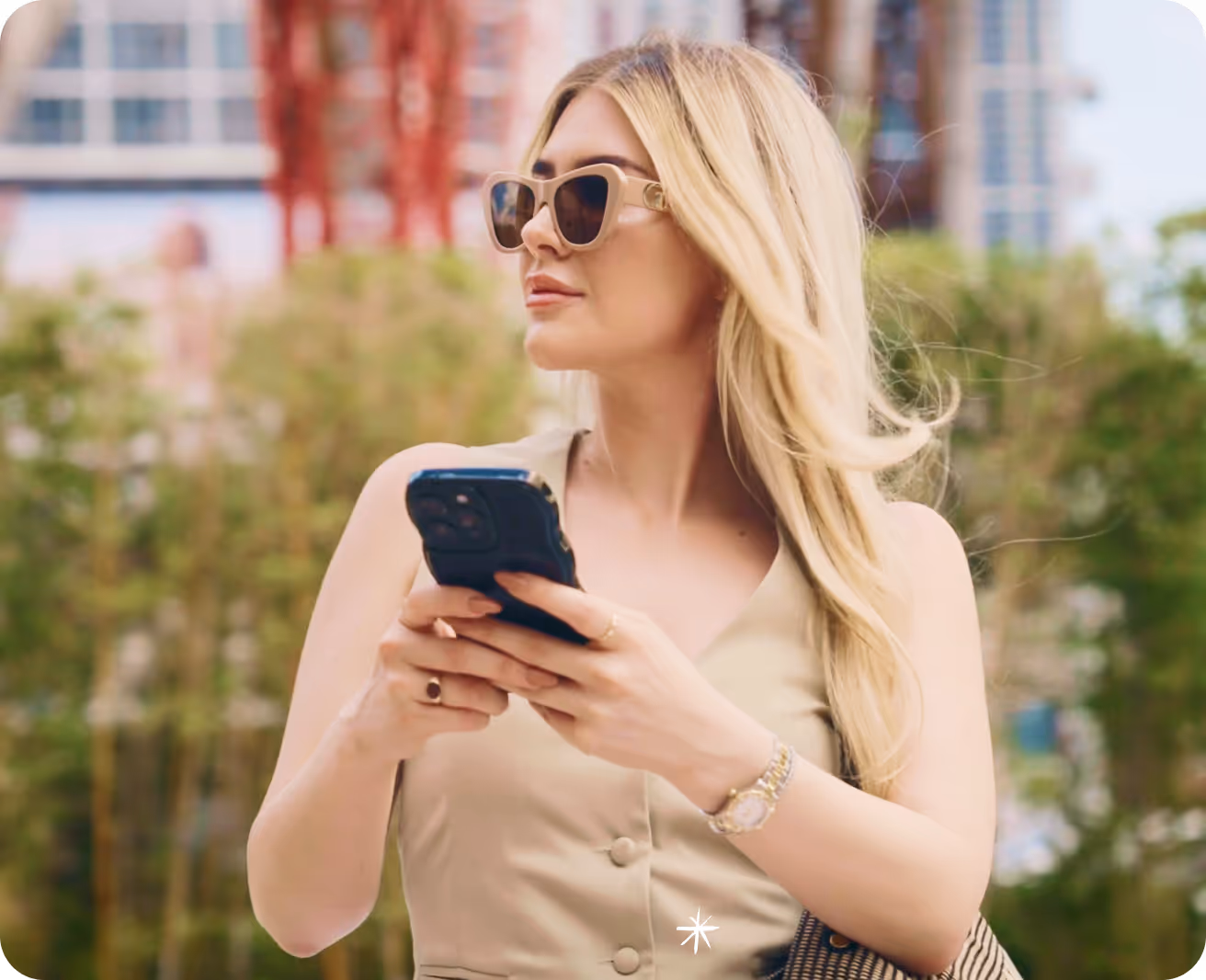 A woman wearing sunglasses looking at her cell phone.