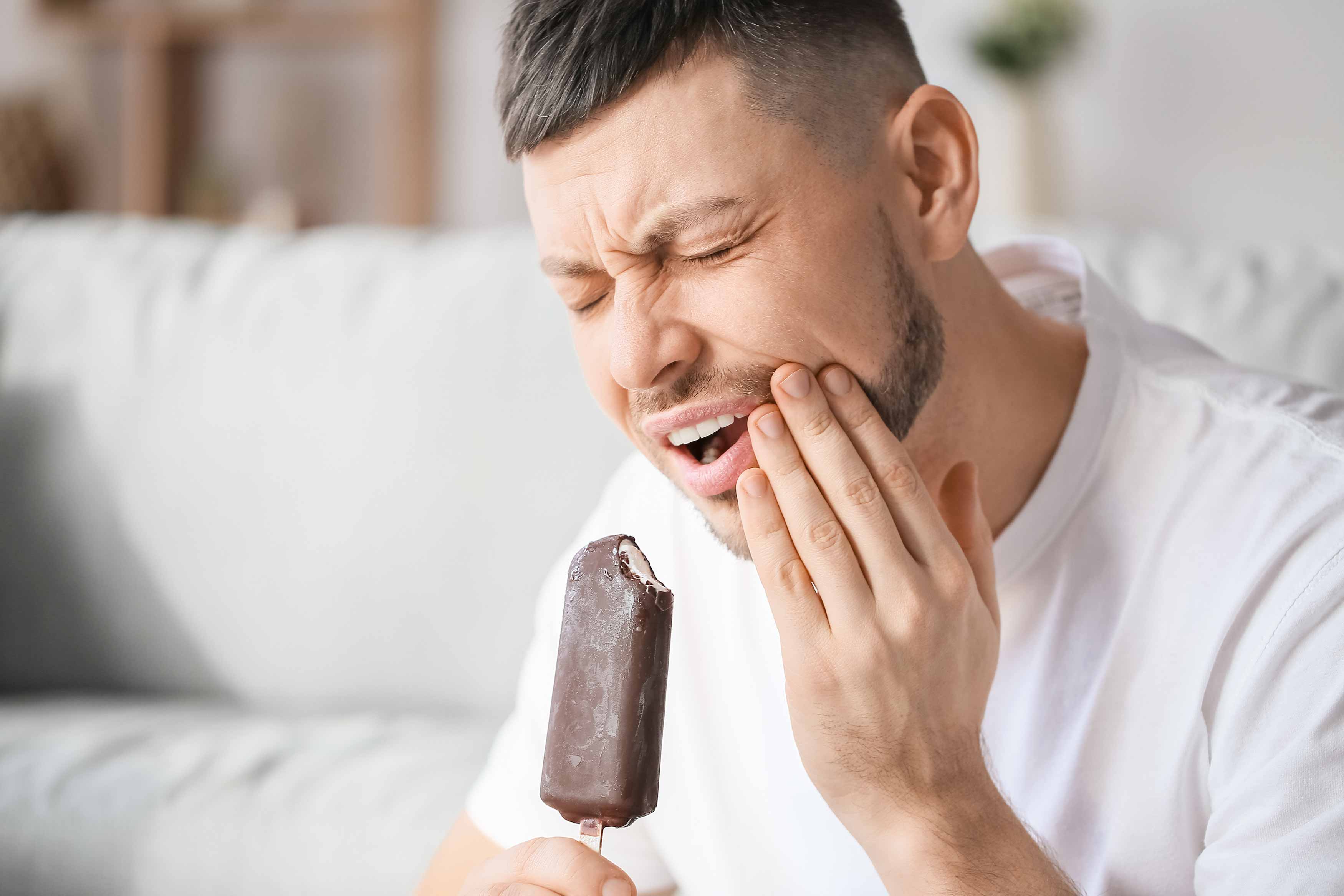 Young male having strong toothache pain after eating a chocolate icecream