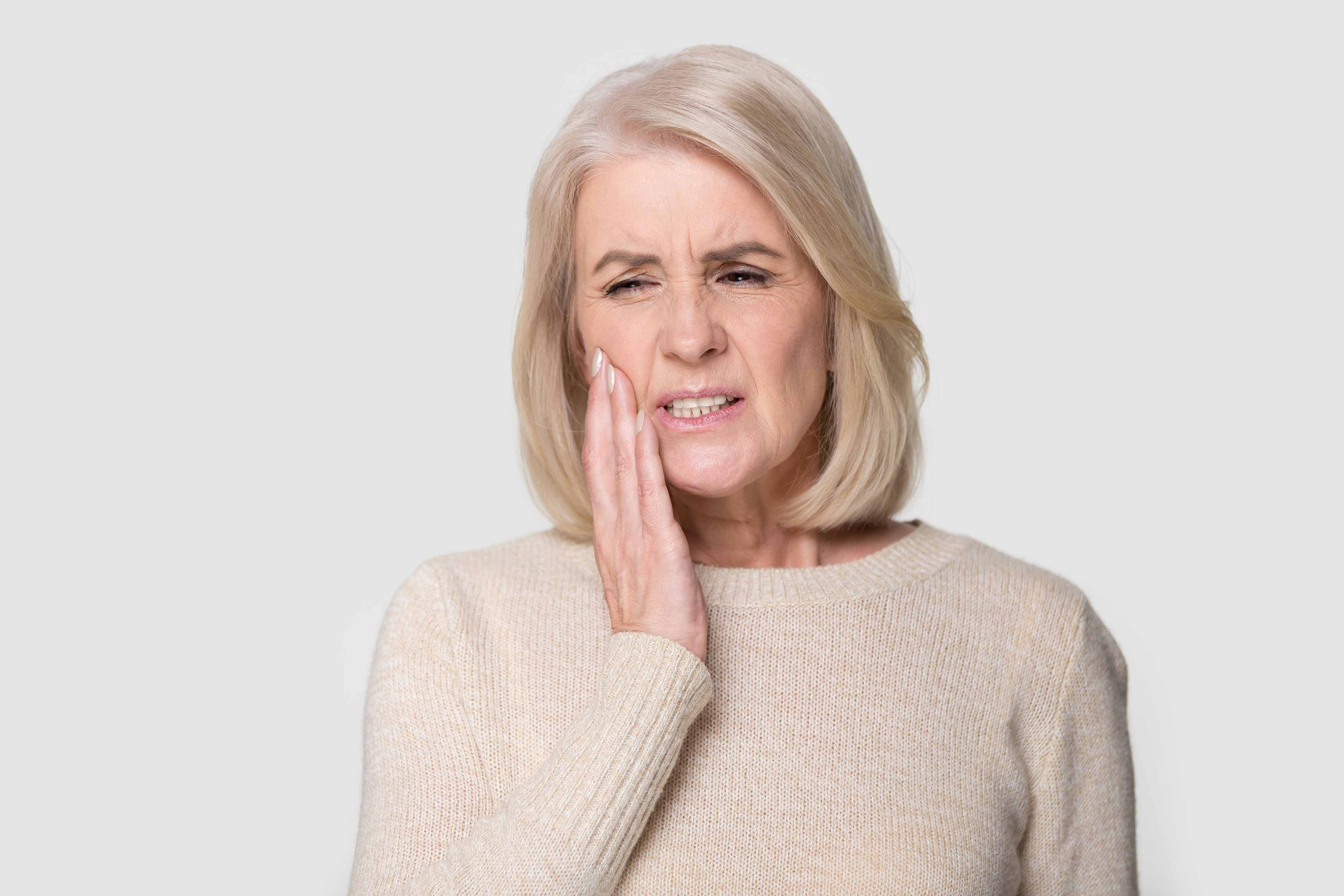 Middle-aged female putting her hand on her lower jaw in reaction to having a tootache.