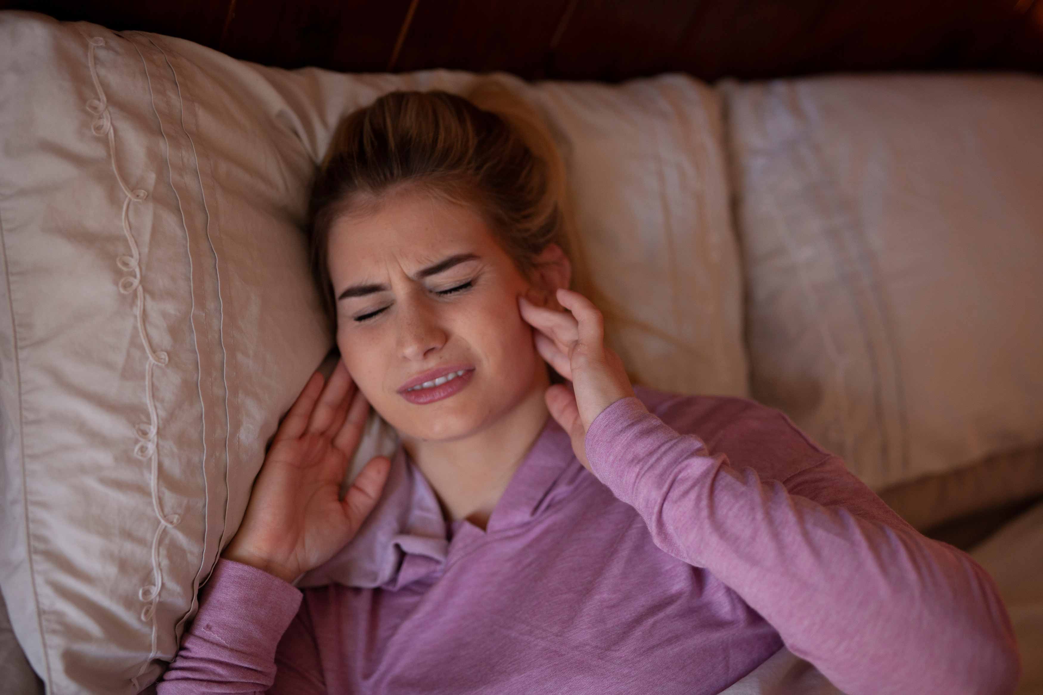 Female holding both her hands to her jaw in pain