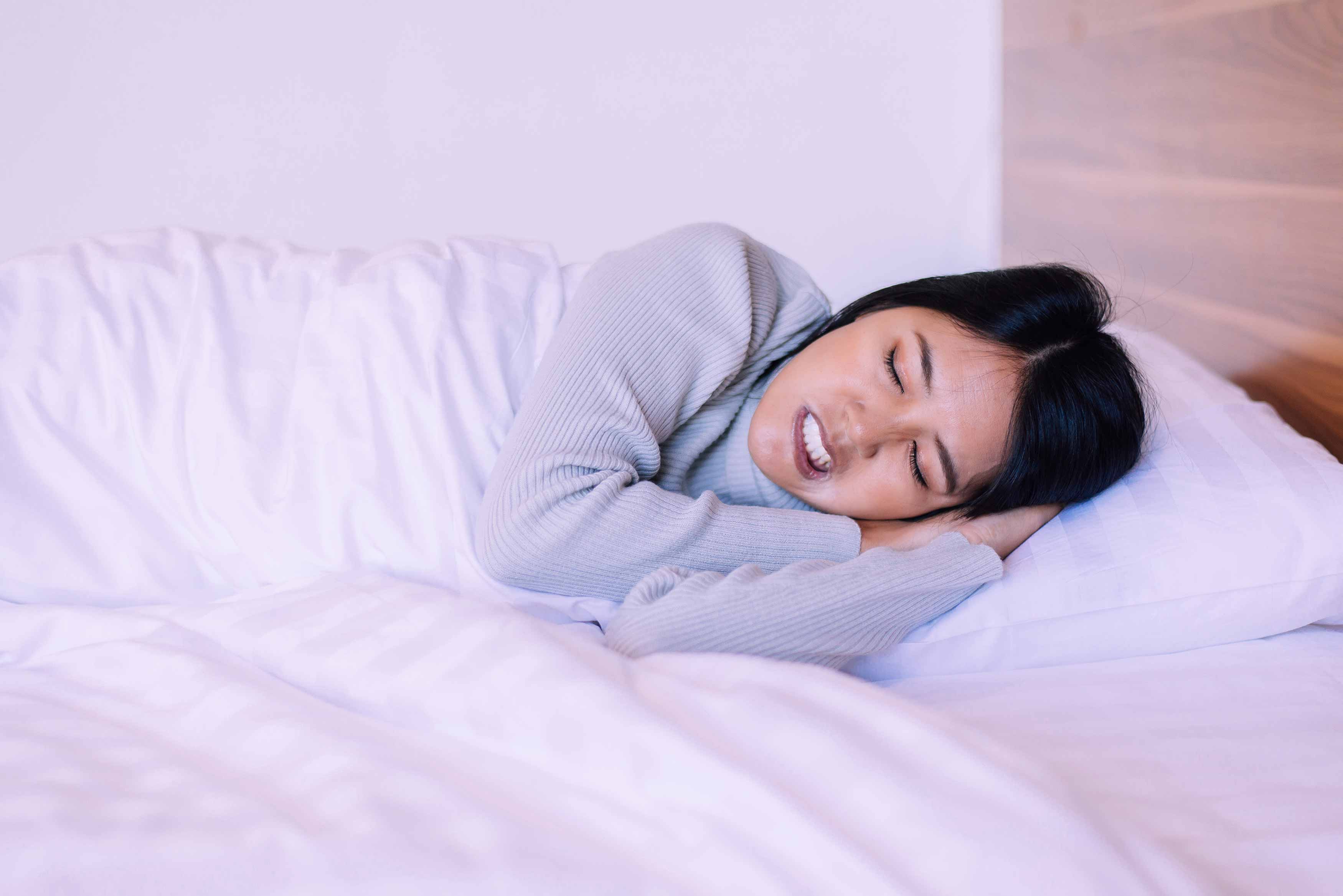 Female sleeping on her side in bed grinding her teeth