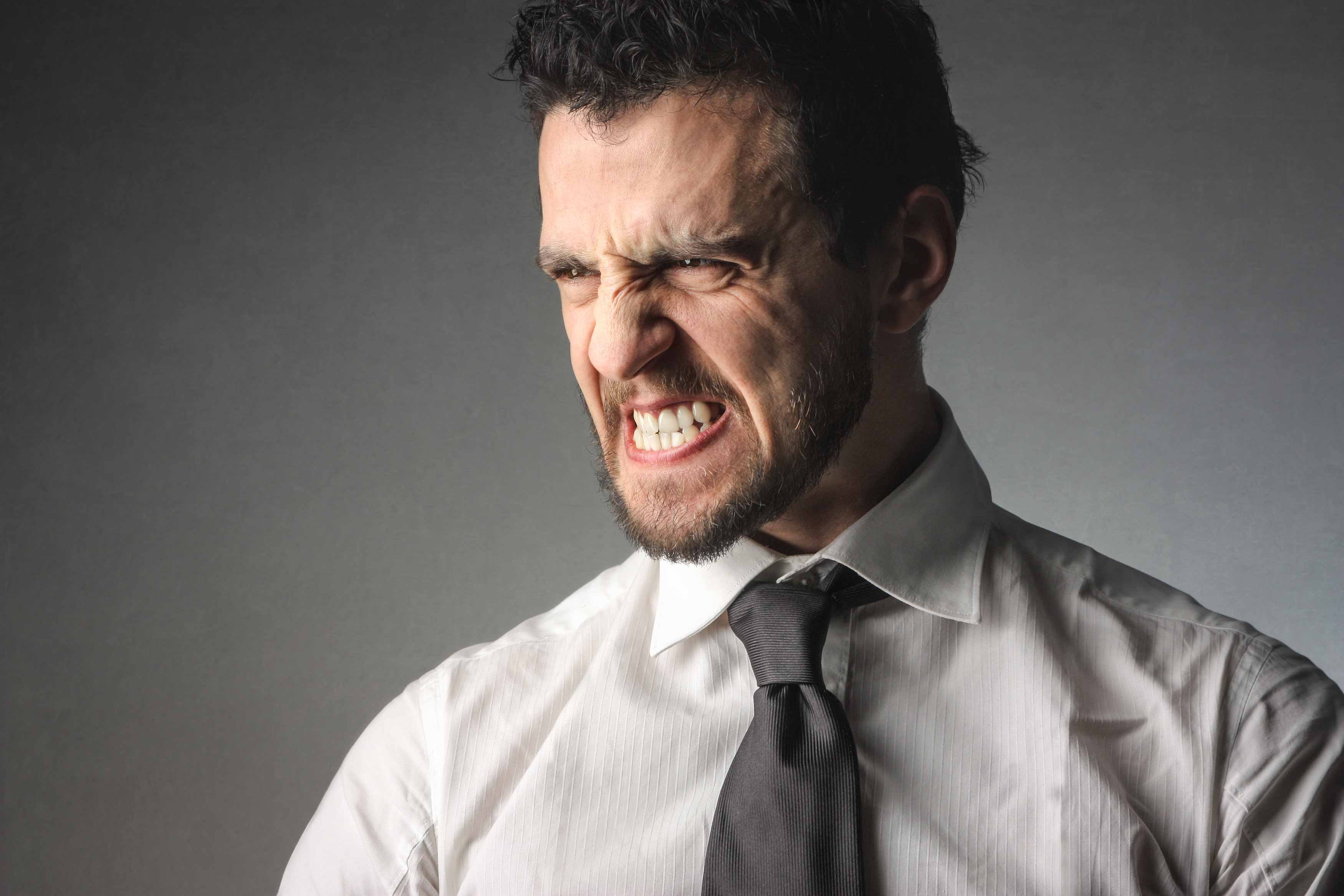 a midbody male photo showing him closing his eyes and clenching his teeth really hard. it also shows the tensenes in his jaw muscles as he clenches