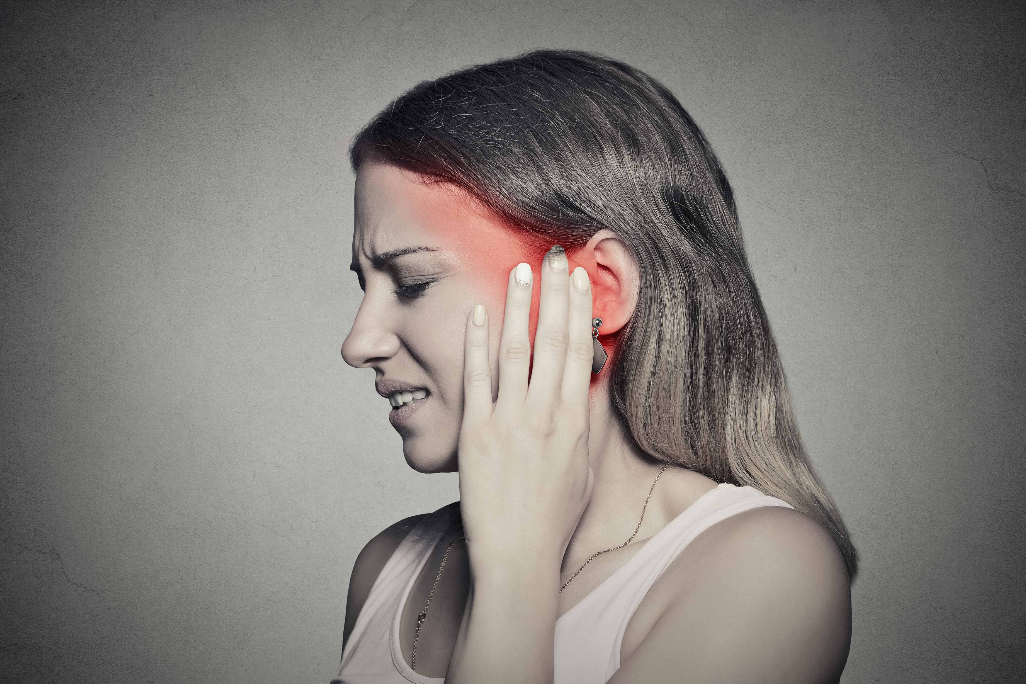 Female holding her left jaw muscle because of radiating pain going up her left jaw masseter and tempolaris muscle