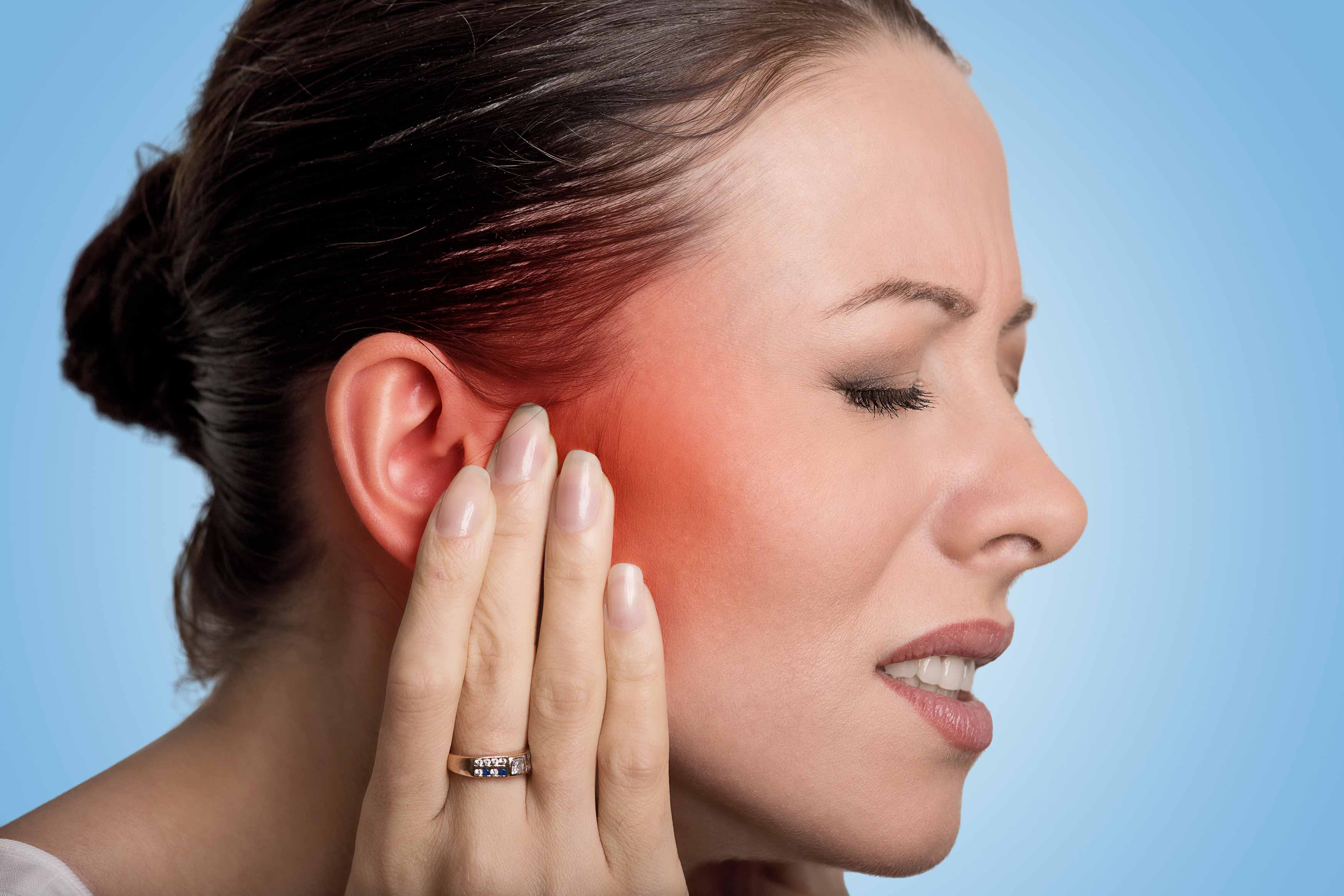 Female holding her right temporomandibular joint (TMJ) because of radiating pain going up her right temple