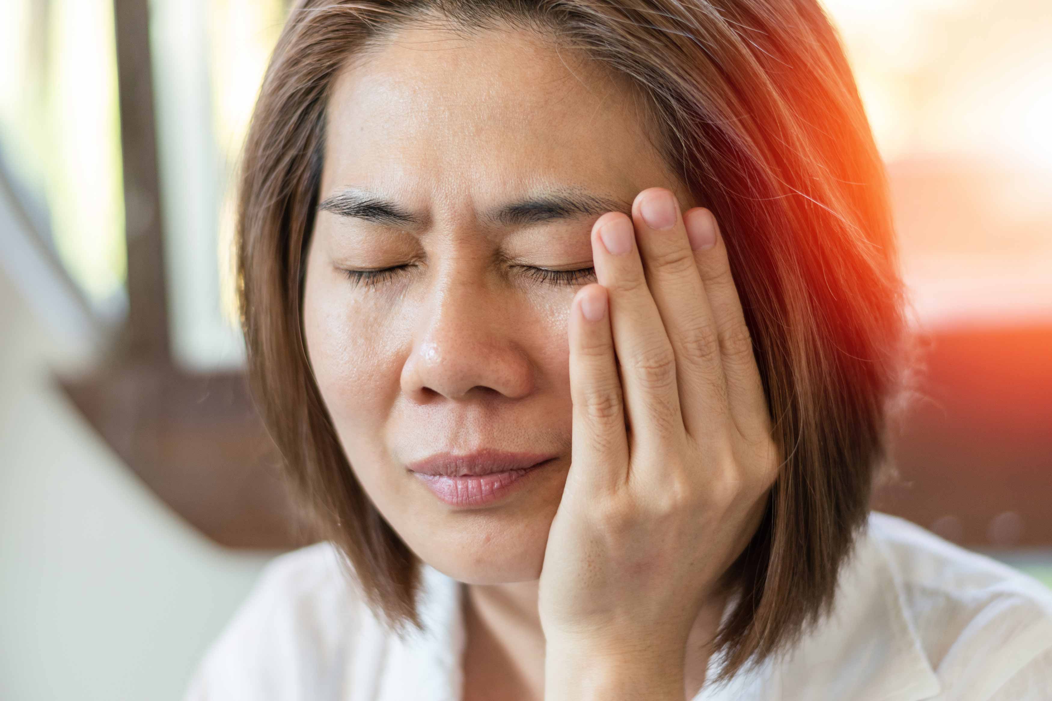 Female holding her left jaw muscle because of radiating pain going up her left jaw masseter and tempolaris muscle