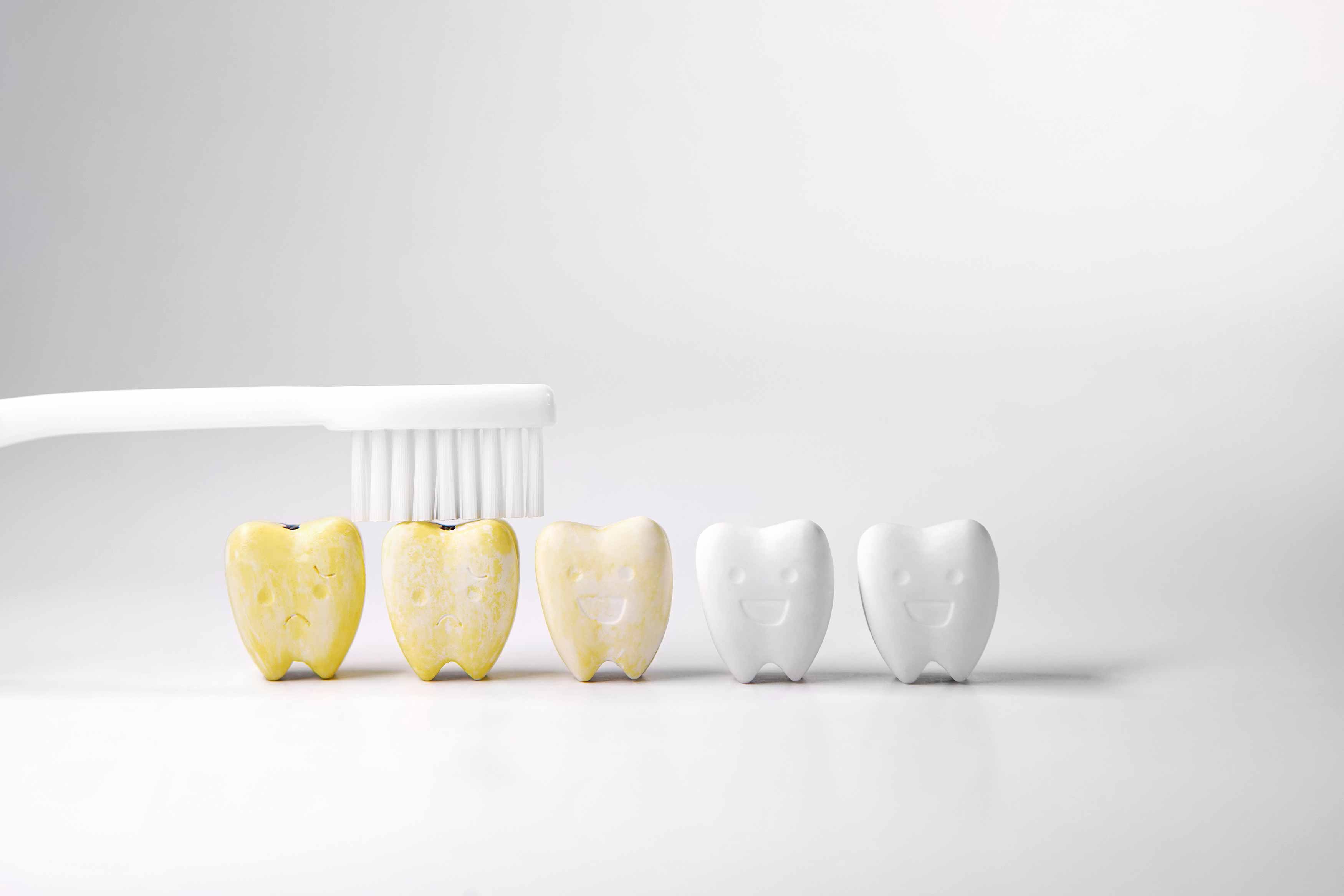 artificial photo of 5 teeth with the left most one being the yellowest and gradually getting whiter with the right most one being the whitest. 