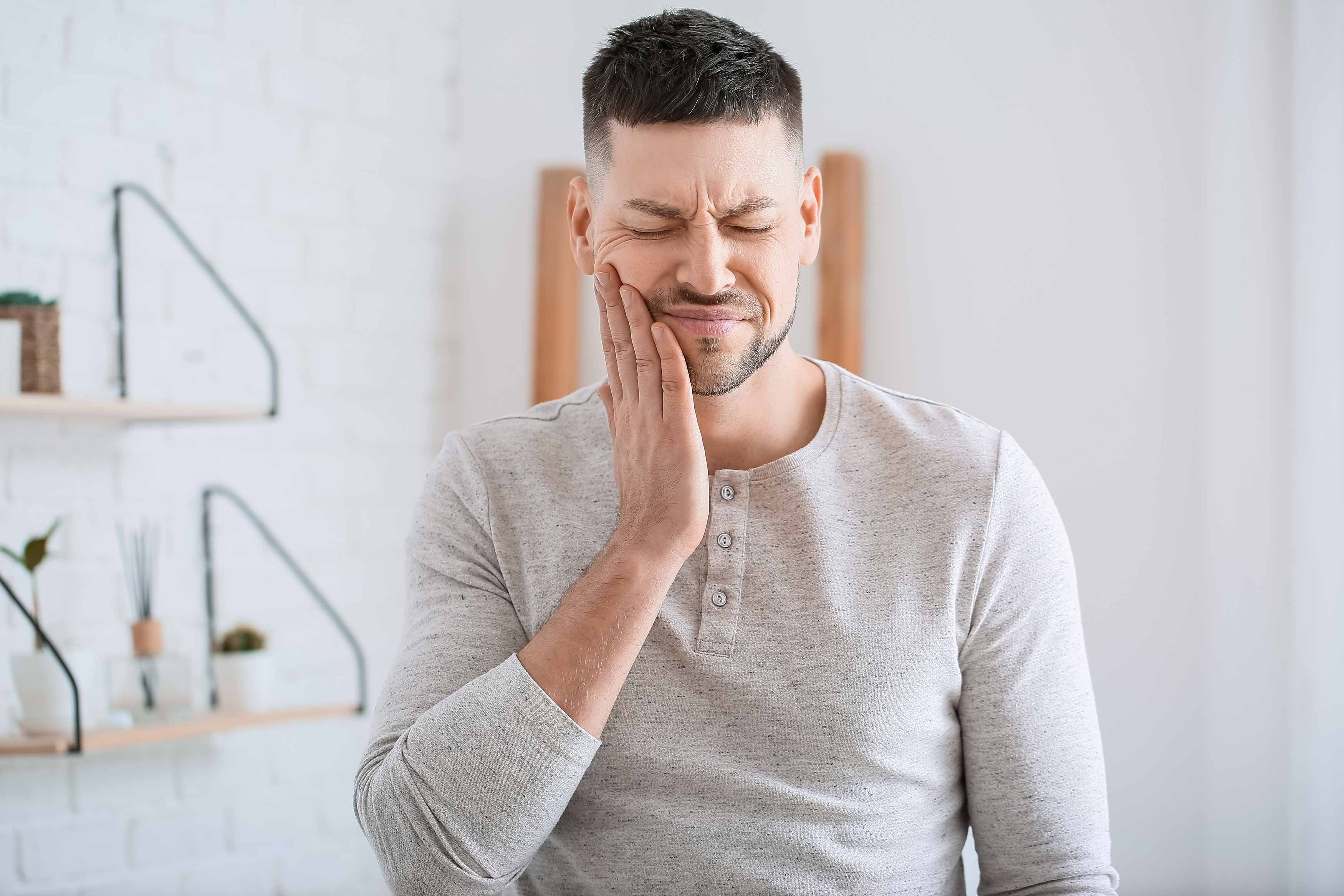 Photo of a man holding his lower right jaw because of a tooth ache