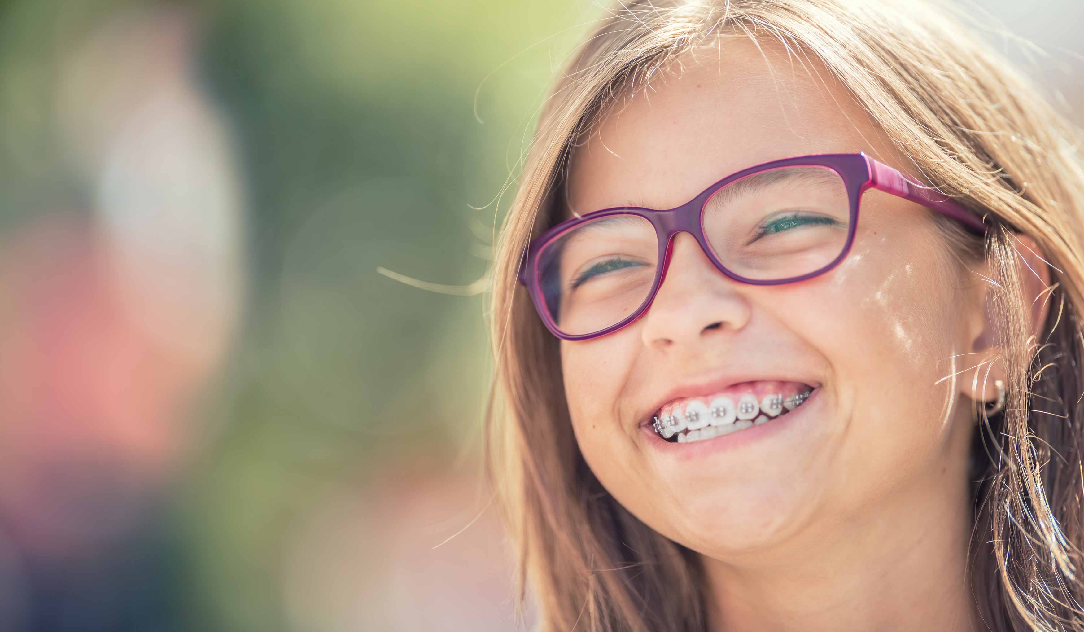 Photo of a young girl who is nearly finished with braces smiling broadly. 