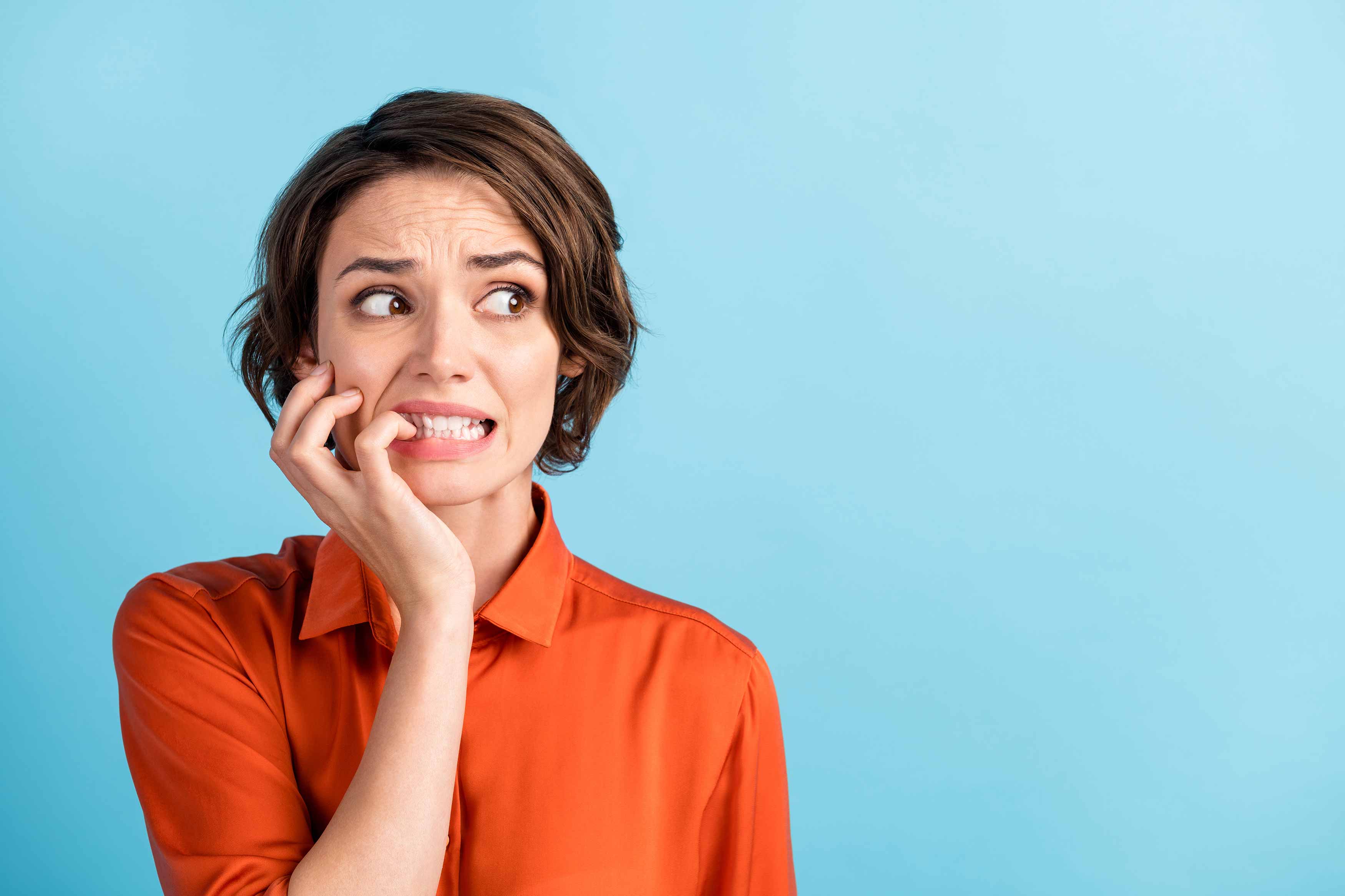 Worried woman biting her nails and looking anxious, expressing concern about oral health issues like bleeding gums or gum disease