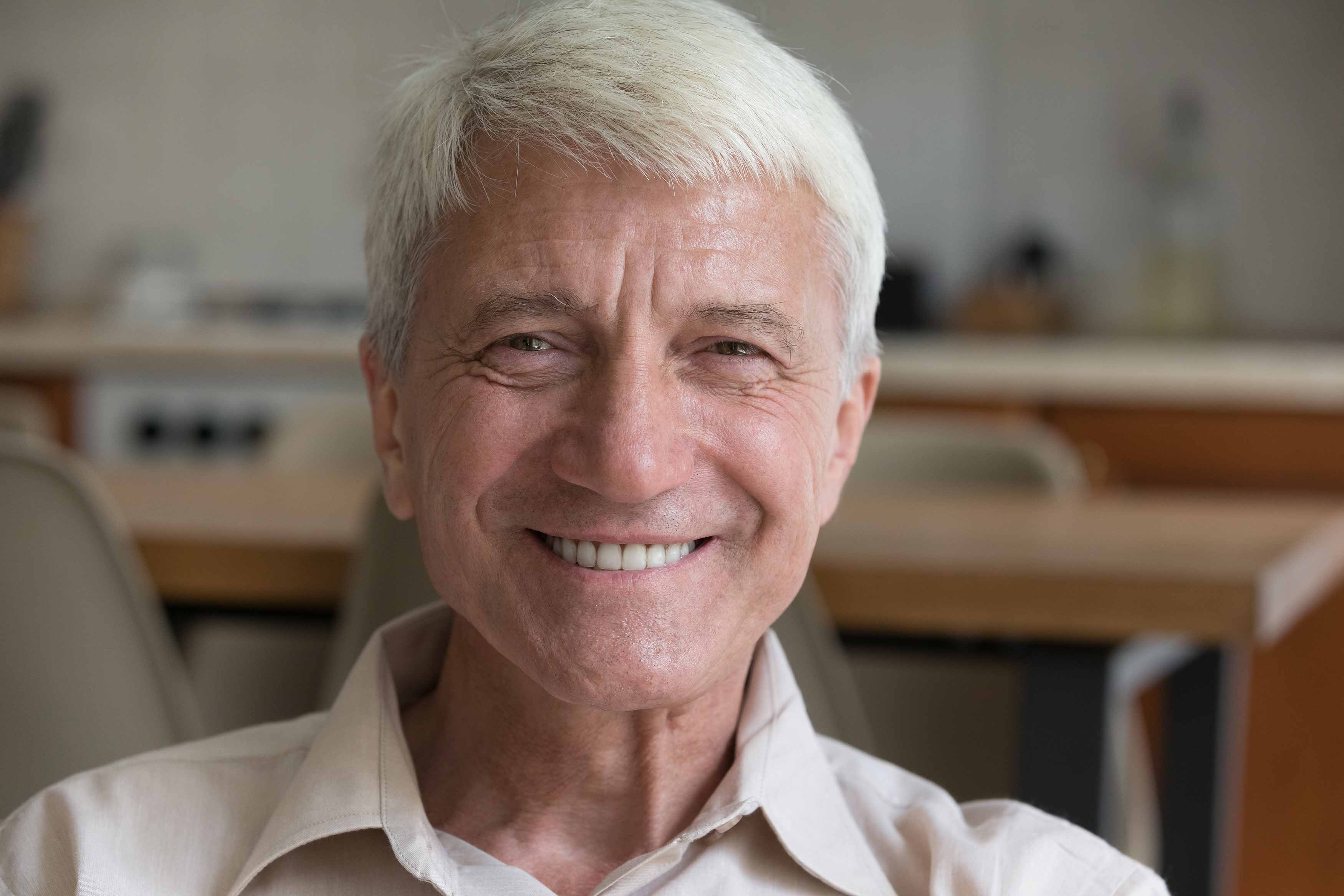 a closeup photo of a smiling older gentleman showing his teeth