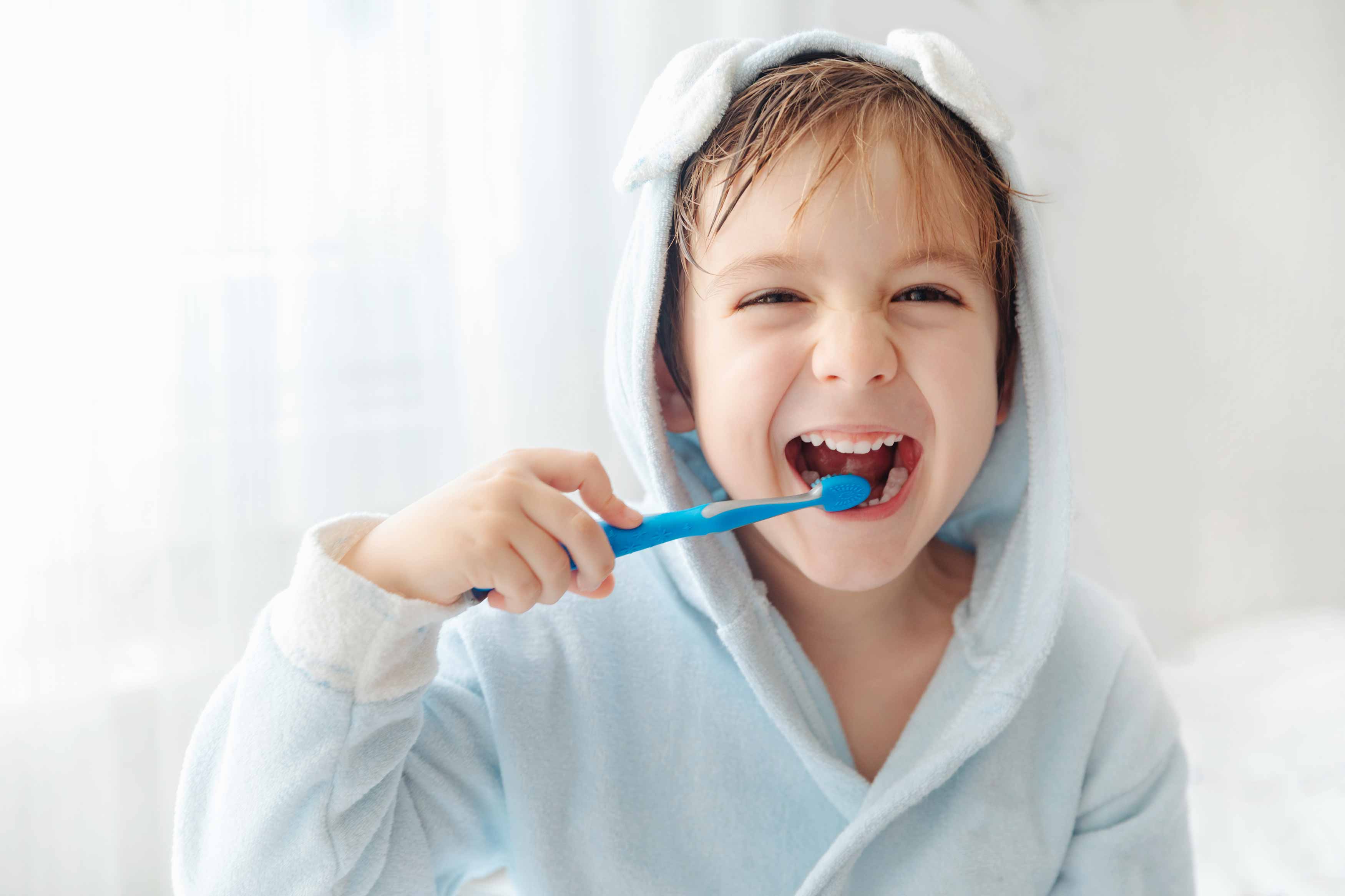 Photo of a boy brushing his teeth with his right hand