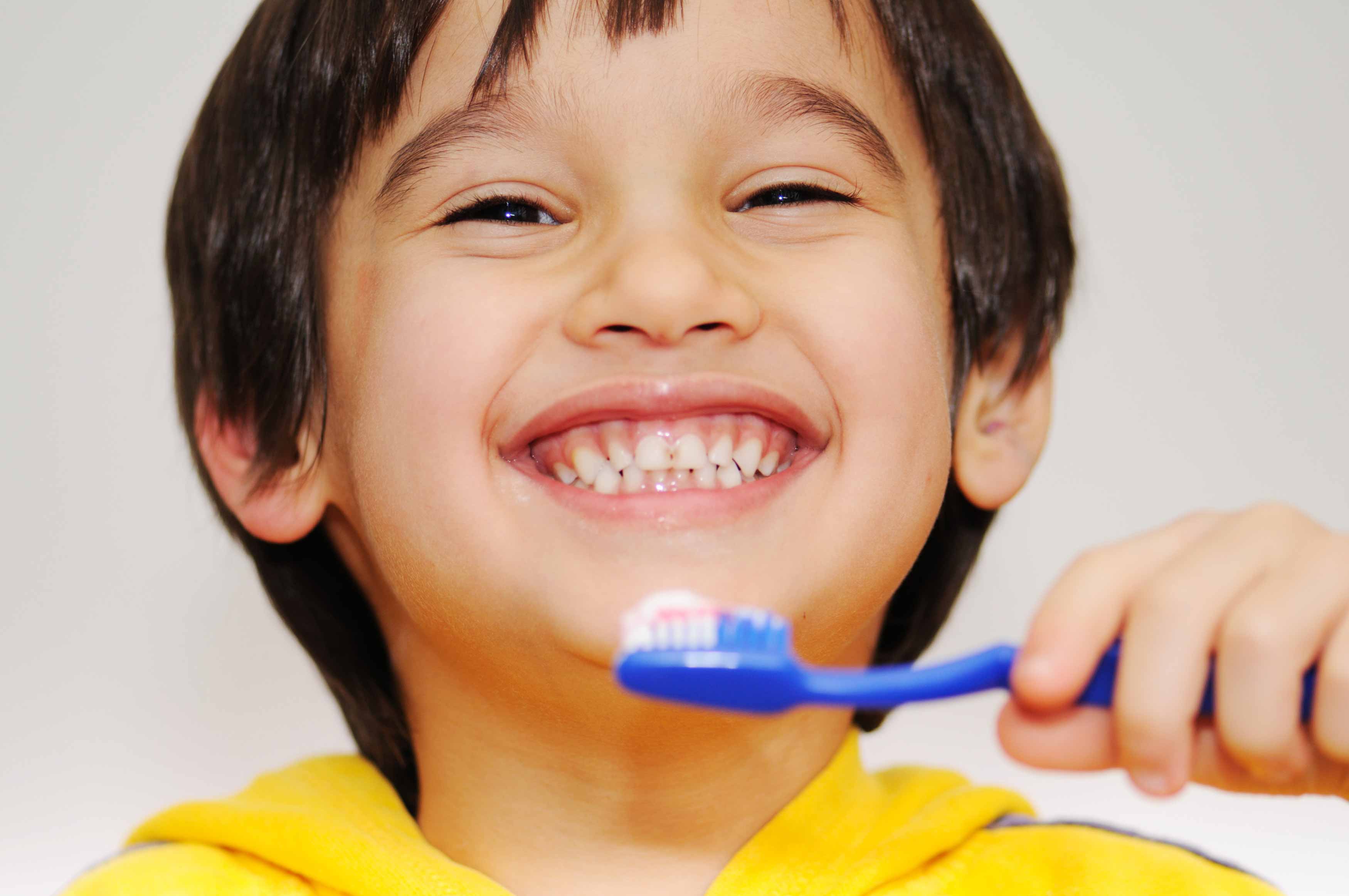 Photo of a boy brushing his teeth with his left hand