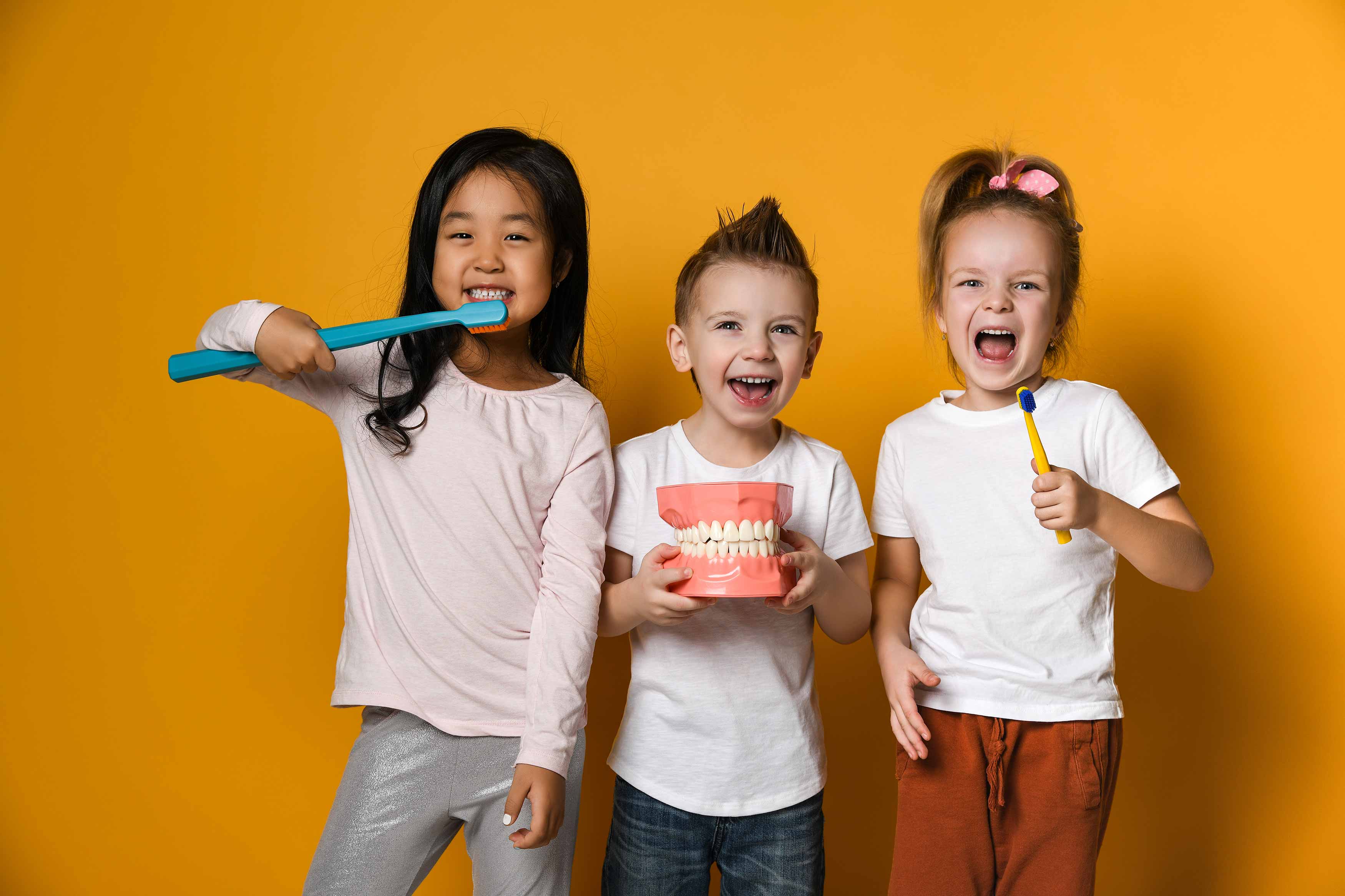 Photo of 3 kids brushing brushing their teeth