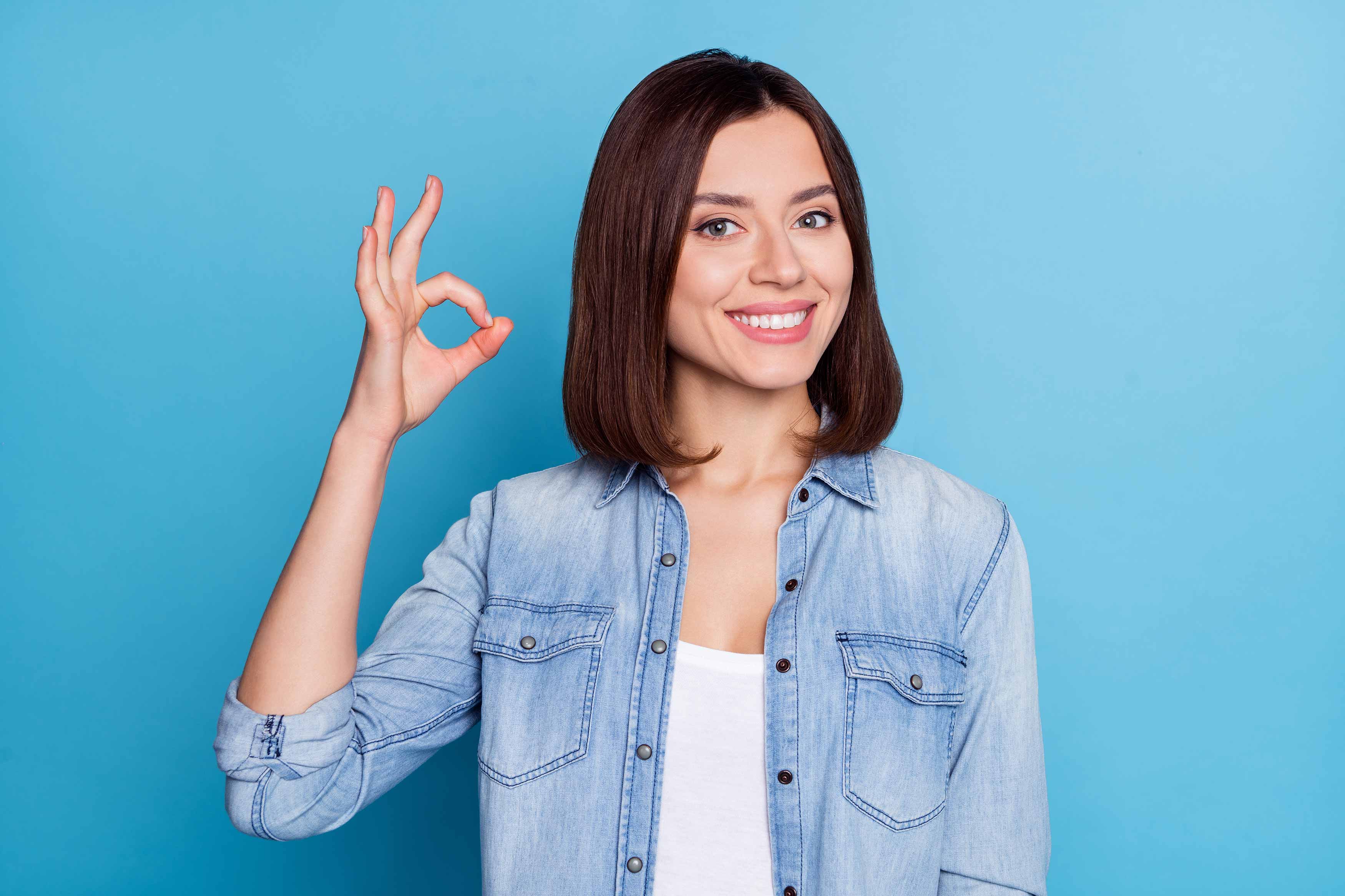 Photo of a young female holding up an OK sign with her right hand