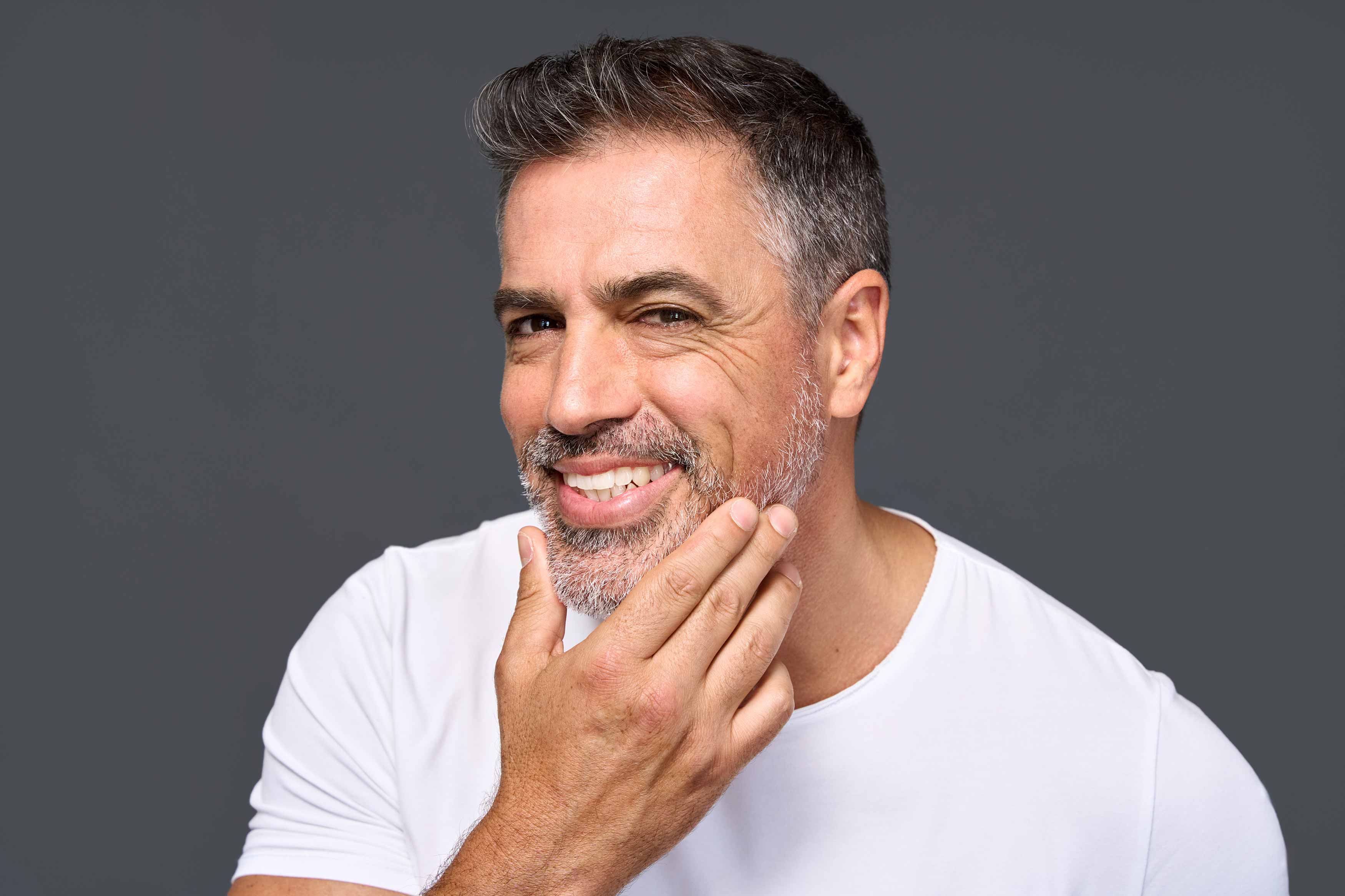 Photo of a male holding his jaw with his left hand and appears to be looking at himself