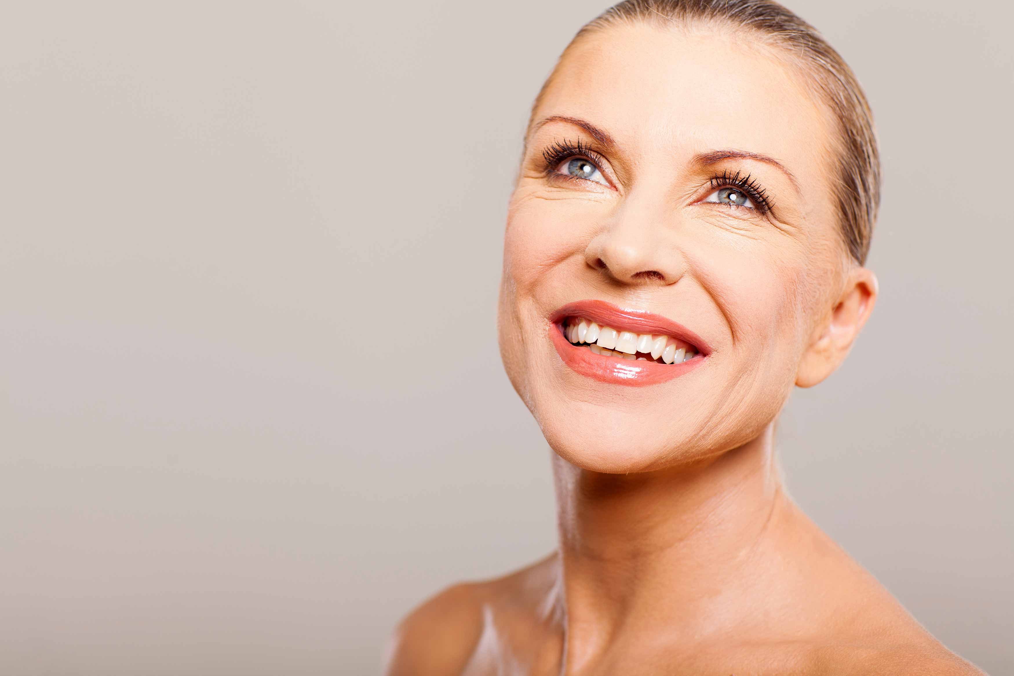 A photo of an elderly lady showing through her smile while gazing upwards