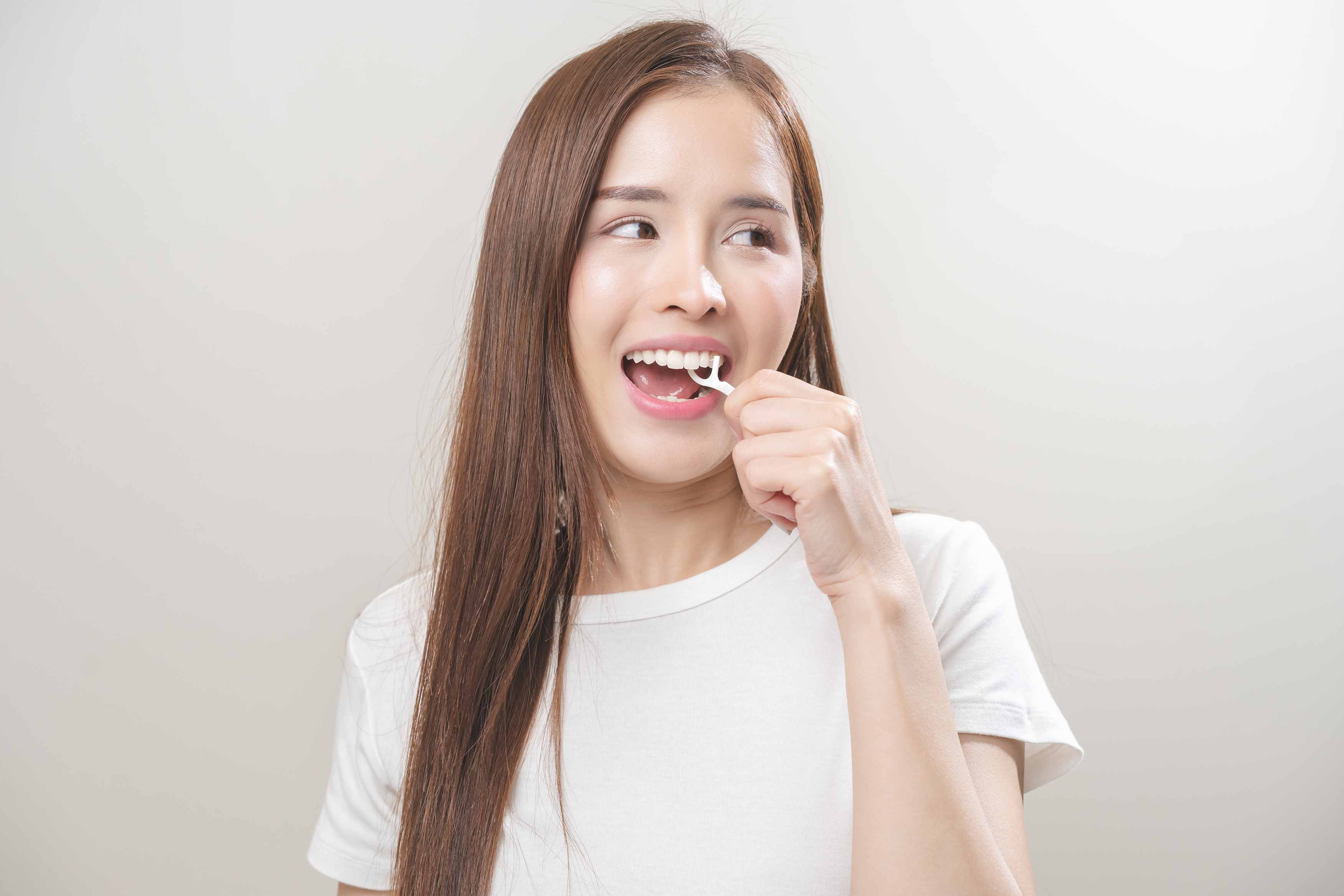 A photo of a female using a dental floss stick