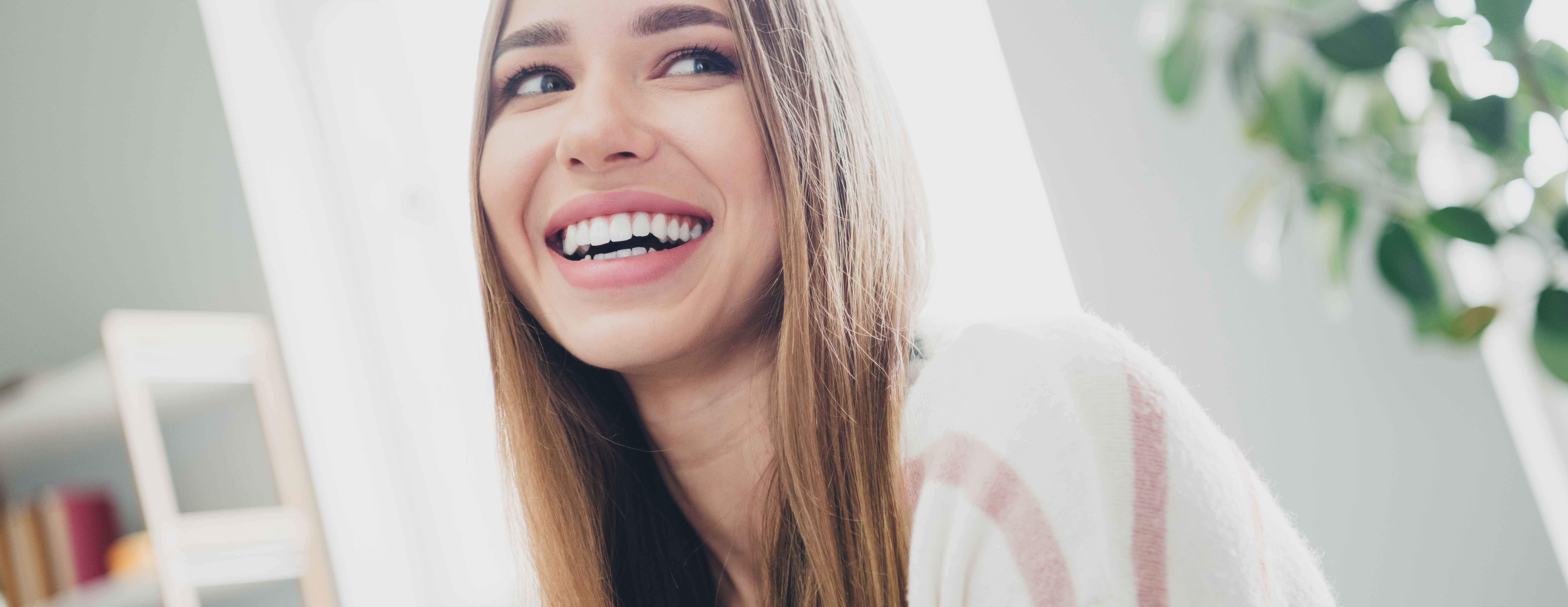 Young woman enjoying a relaxing day at home in natural daylight, smiling in the living room, capturing moments of joy and tranquility after getting a clean by dentists of hawthorn