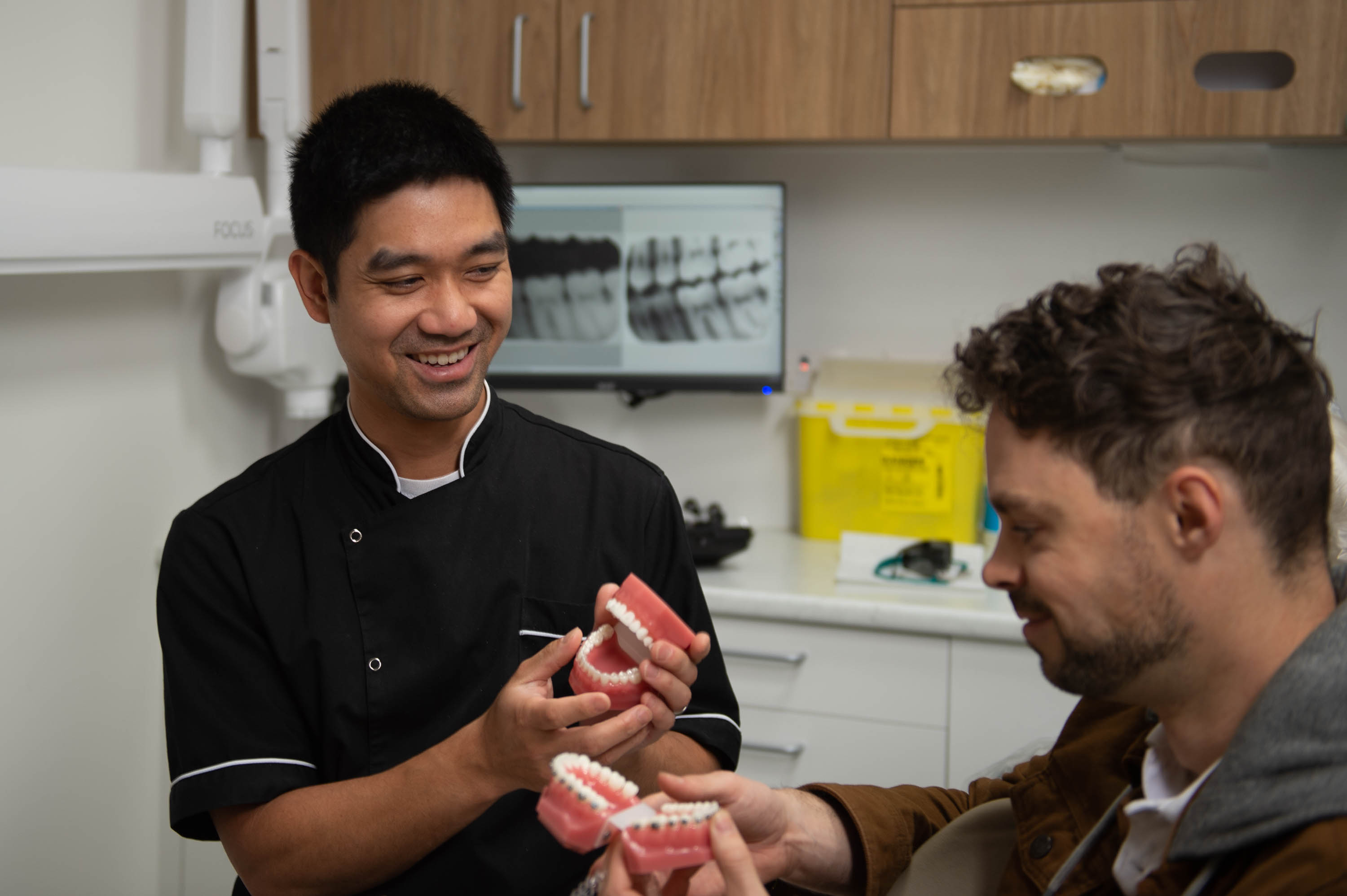Photo of Dr Aaron Wong showing off a model of teeth to a patient