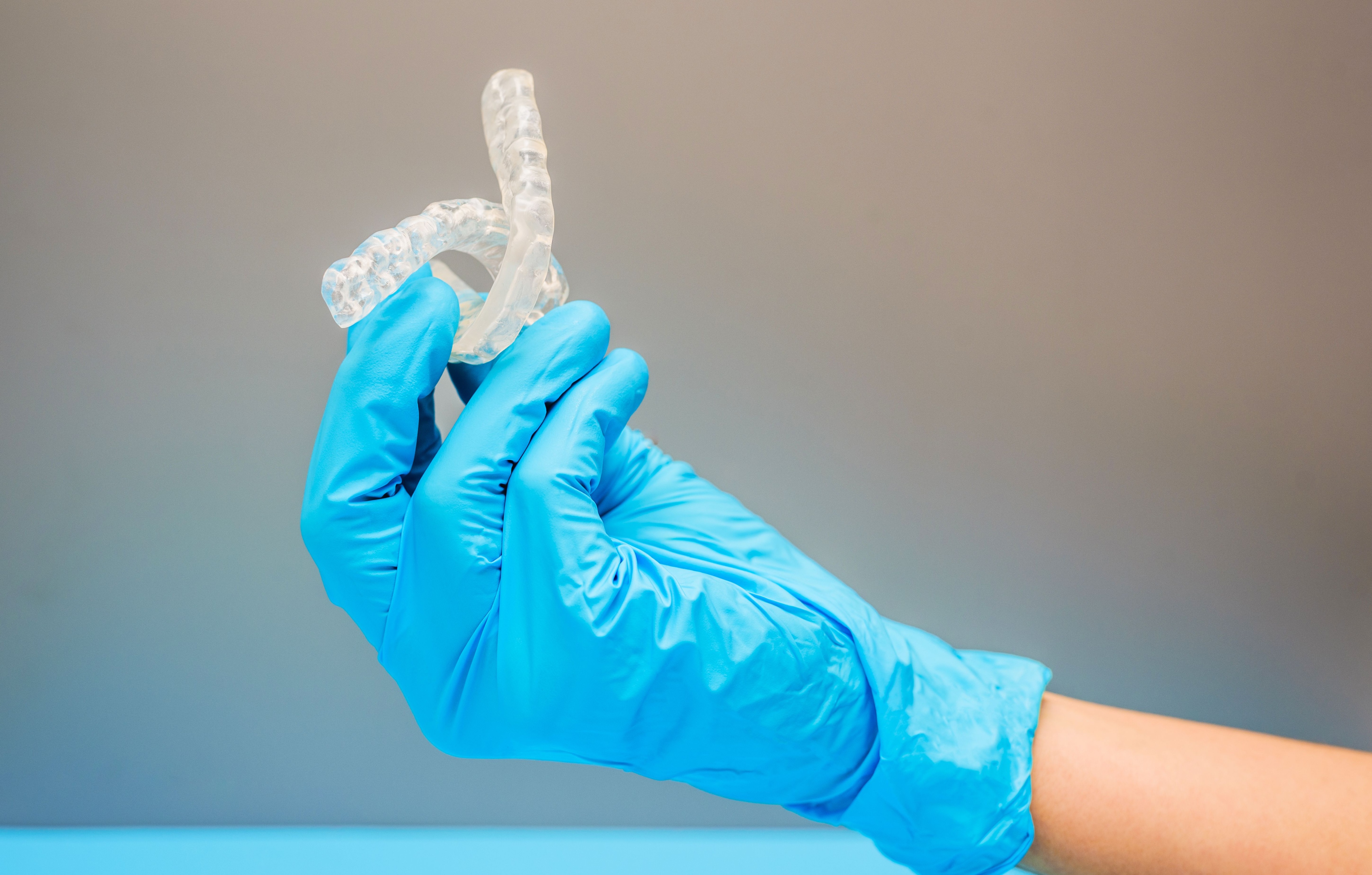 Photo of someone holding up two dental appliances in his right hand 