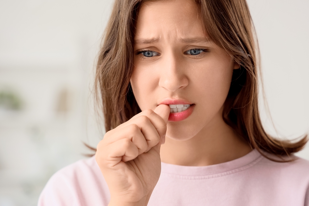 Beautiful young thoughtful and stressful woman in living room at home