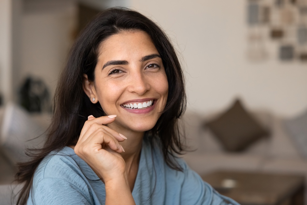 Close-up portrait of a woman relaxing indoor, look at camera with joyful expression, exuding happiness, enjoy pleasant time at home, advertising dental services while revealing her white teeth