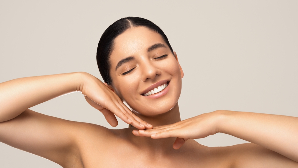 Beauty portrait of cheerful beautiful woman smiling with eyes closed tilted head and gentle hands next to face